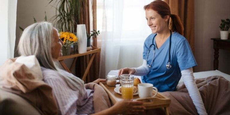 Female Nurse Serving Breakfast to Resident in Assisted Living Facility